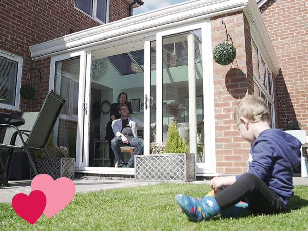 The Morleys watching their son in the garden from their conservatory